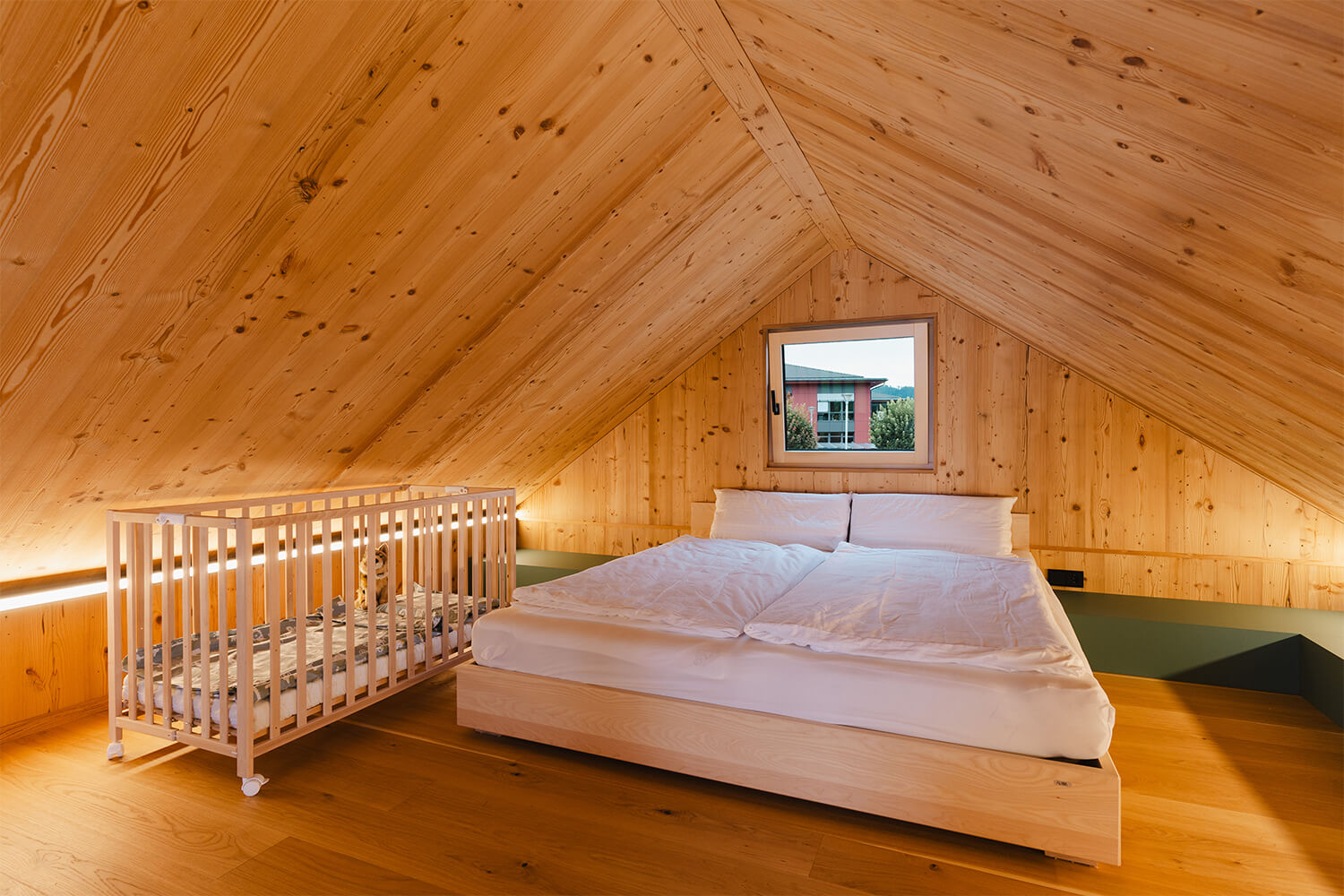 Individuell konfigurierbares Tiny Haus von WOLF Haus mit gem&uuml;tlichem Schlafzimmer, Holzdecke, Doppelbett und Babybett im Dachgeschoss